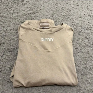 Beige tröja från Aim'n - Säljer en snygg beige tröja från Aim'n. Den är perfekt för en avslappnad stil och har en enkel design med Aim'n-loggan på bröstet. Tröjan är i bra skick och passar perfekt till träning eller vardags 