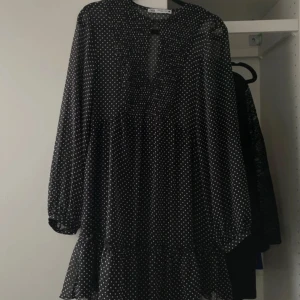 Svart prickig klänning - En jättefin svart klänning med vita prickar. Använd 1-2 gånger. Den har långa ärmar och en volangdetalj vid fållen, och knäppning där fram💓är i strl xs men passa mig som är s-m 