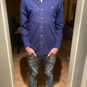 Blå skjorta från Ralph Lauren - Säljer en stilren blå skjorta från Ralph Lauren i slim fit.  Den är i bra skick och storlek S. Inga byten. Modellen är 177 och väger 64. Hör av dig vid minsta funderingar