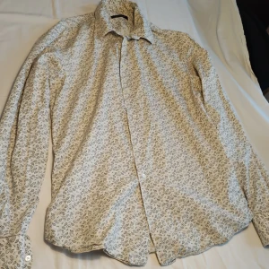 Mönstrad skjorta från Paul & Friends - Snygg skjorta från Paul & Friends med ett diskret mönster i svart och beige. Skjortan har långa ärmar och knappar framtill. Perfekt för en stilren look.