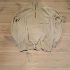 Beige fleece tröja med dragkedja - Säljer en beige fleece tröja med halv dragkedja och bröstficka. Perfekt för kyliga dagar med sin mjuka och varma känsla. Tröjan har långa ärmar och en avslappnad passform. Skriv för frågor och mått osv