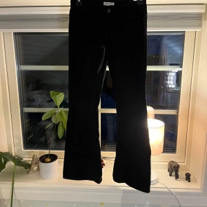 Svarta bootcut jeans från Lindex storlek 152 - Snygga svarta bootcut jeans från Lindex i storlek 152. De har en klassisk femficksdesign och stängs med knapp och dragkedja. Perfekta för en stilren look. Justerbar midja. Lågmidjade!