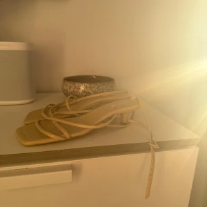 Beige sandaler med remmar - Snygga beige sandaler med tunna remmar och fyrkantig tå. Perfekta för varma sommardagar och ger en stilren look. De har en justerbar rem runt ankeln för bättre passform.