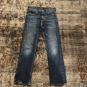 Blå jeans från Replay - Snygga blå jeans från Replay med klassisk femficksdesign och diskreta slitningar. De har en rak passform och är perfekta för en avslappnad stil. Märkesdetaljer syns på fickan och insidan av midjan.