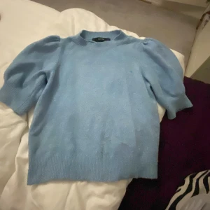 Ljusblå stickad tröja från Vero Moda - Säljer en ljusblå stickad tröja från Vero Moda. Tröjan har puffiga ärmar och en rund halsringning. Perfekt för kyligare dagar. 