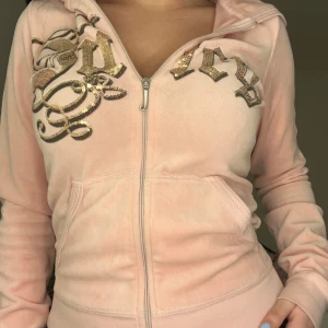 Rosa kofta från Juicy Couture - Säljer en snygg rosa hoodie från Juicy Couture med glittriga paljettdetaljer på bröstet. Köpte denna på Sellphy, den har några små fläckar på vissa ställen (som syns på sista bilden) men de är inte så jättesynliga🩷Det är storlek S men tycker den passar mer som en XS
