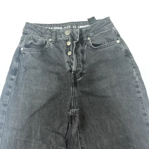 Svarta jeans med hög midja - Snygga svarta jeans med hög midja och knappgylf. De har en regular wide passform och är perfekta för en avslappnad stil. Storlek 25 med längd 32.