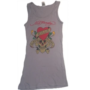 Linne från Ed Hardy - Säljer ett coolt linne från Ed Hardy med ett stort tryck av en dödskalle och texten 'Love Kills Slowly' på framsidan. I bra skick och står onesize och passar på mig som normalt använder xs. Den är väldigt stretchig och skulle tro att den passar storlekarna xs- m 