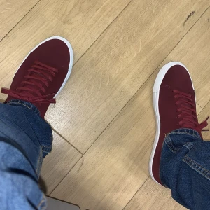 Röda sneakers från Sneaky Steve - Snygga röda sneakers i mocka från Sneaky Steve. Skorna har en stilren design med vita sulor och matchande röda snören. Perfekta för en casual look. Dem är köpta för ca 5 månader sen. Använda ett par få gånger ca 4-7 gånger. Köpte för ca 1600kr.  Pris kan diskuteras. Hör gärna av er om ni har frågor eller funderingar. 