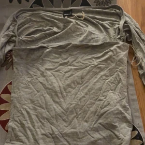 Grå  topp från Gina Tricot - Säljer en stilren grå topp från Gina Tricot. Toppen har långa ärmar och är tillverkad i ett mjukt bomullsmaterial. Perfekt för en avslappnad och trendig look.