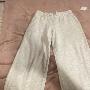 Grå mjukisbyxor med snörning - Säljer ett par bekväma grå mjukisbyxor med elastisk midja och snörning. Byxorna har praktiska fickor framtill och är perfekta för en avslappnad stil. De är tillverkade i ett mjukt material som ger en skön känsla.