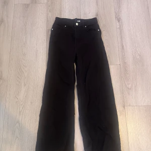 Svarta byxor - Snygga svarta byxor med hög midja och raka ben. Perfekta för en stilren look. Byxorna har knappar och dragkedja framtill.