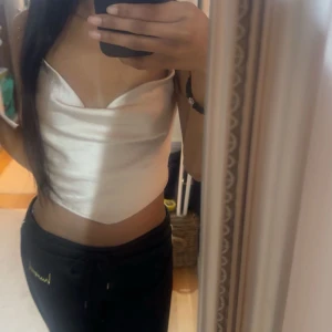 Vit satinlinnetopp med öppen rygg - Xs Snygg beige satinlinnetopp med öppen rygg och knytband. Perfekt för en stilren och elegant look. Toppen är ärmlös och har en smickrande passform. Från Gina andvänt 2-3 gånger.