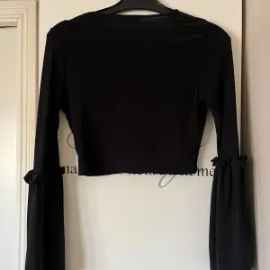 Snygg svart croppad topp från PrettyLittleThing med långa vida ärmar och v-ringning. Superfina armar. 
