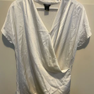 Vit omlottopp från Lindex - Säljer en stilren vit omlottopp från Lindex. I storlek M 