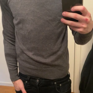 Grå tröja från Uniqlo - Säljer en stilren grå tröja från Uniqlo. Tröjan är långärmad och tillverkad i 100% merino. Enkel design som funkar till det mesta. 