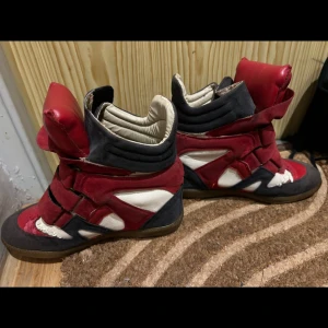Röda och blåa sneakers med hög krage - Unika sneakers i rött och blått. Skorna har en kombination av mocka och syntetmaterial med vita detaljer. Perfekta för en djärv stil. Isabel marant liknande sneakerBörjat tappa lute skinn på vissa platser men inget som märks av.