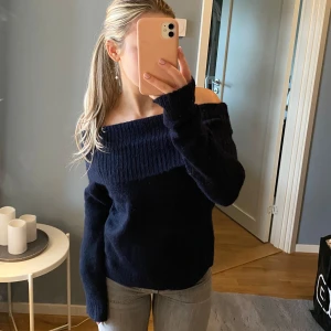 Mörkblå offshoulder tröja - Säljer en snygg mörkblå offshoulder tröja med långa ärmar. Perfekt för en stilren look och passar bra till jeans eller kjol. Tröjan har en ribbad struktur upptill som ger en fin detalj.