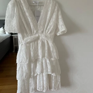 Vit klänning från Chelsea - Vit klänning från Chelsea med v-ringning och korta ärmar. Den är helt oanvänd med prislapp kvar. Storlek M men är insydd i midjan så den är som en S. Perfekt till studenten!  Nypris 500kr.