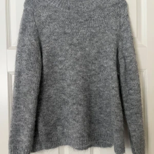 Grå stickad tröja från JDY - Mysig grå stickad tröja från JDY. Perfekt för kyliga dagar med sin mjuka och varma känsla. Tröjan har långa ärmar och en rund halsringning. Ett måste i garderoben för en stilren look. Helt oanvänd pga att den inte kommer till användning, i ett toppen skick!💖✨