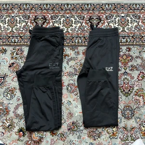 Svarta mjukisbyxor från Emporio Armani - Snygga svarta mjukisbyxor från Emporio Armani. Byxorna har elastisk midja med dragsko och ribbade muddar vid bensluten. Perfekta för en avslappnad stil. Använd bara 2 gånger så de är på ett jätte bra skick10/10 väldigt skönt och sportig 