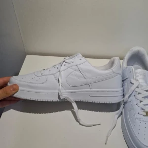 Vita Nike Air Force 1 sneakers Storlek 42 - Säljer ett par klassiska vita Nike Air Force 1 sneakers. Skorna har en stilren design med snörning och den ikoniska Nike-loggan på sidan. Perfekta för en casual look. Oanvända helt nya skor. skicka meddelande via frågor