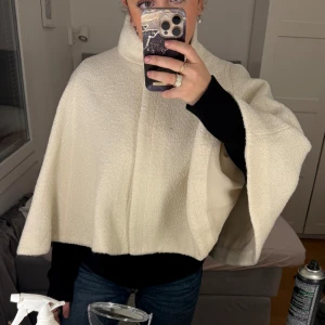 Beige cape från Zara - Säljer en stilren beige cape från Zara. Den har en hög krage och knappar framtill. Perfekt för att lägga till en touch av elegans till din outfit. 🧥✨helt ny och oanvänd. Den är i storlek XL men jätte liten i storleken så passar som en M, billigare frakt på min vinted, skriv om ni vill ha den ❤️