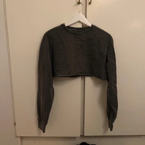 Grå croppad tröja - Säljer en grå croppad tröja. Tröjan har långa ärmar och en avslappnad passform. Perfekt för en casual look. I ett mycket bra skick!