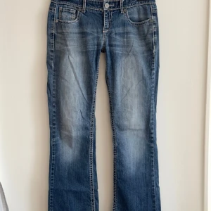 Lågmidjade bootcut jeans - Väldigt lågmidjade bootcut jeans med fina detaljer i bak. Har vit stiching och har snöre i midjan så man kan tighta till. Liknar miss me. Har en liten liten fläck på höger ben. Passar M/S. Är lite för stora för mig, så om bilder förfrågas så kommer de sitta lite pösigt. Skriv gärna vid frågor