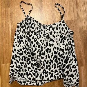 Leopardmönstrad linnetopp från Gina Tricot - Säljer en snygg leopardmönstrad linnetopp från Gina Tricot. Toppen har smala axelband och en lös passform, perfekt för en avslappnad stil. Den är i svart och vit färg och passar bra till jeans eller kjol. Kommer i bra skick💝 tar inga returer!💝