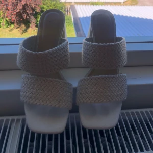 Beige sandaler med klack från H&M - Snygga beige sandaler med klack från H&M. De har en flätad design och breda remmar som ger en stilren look. Perfekta för sommarens alla tillfällen. Storlek 38 