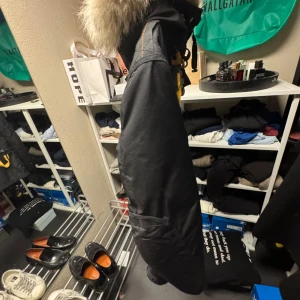 Svart parajumper vinterjacka - Snygg svart Parajumper med pälsdetalj på huvan. Jackan har flera fickor och en broderad patch på ärmen. Den har en dragkedja framtill och är perfekt för kyligare väder. Kvitto finns ej men den är äkta.                                                               priset är ej hugget i sten 