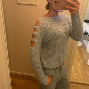 Ljusblå stickad tröja med cut out - Säljer en snygg ljusblå stickad tröja med cut outs på armarna. Tröjan har långa ärmar och en bekväm passform. I väldigt bra skick och storlek S!