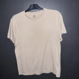 Beige t-shirt från H&M - Säljer en beige t-shirt från H&M i regular fit. Den har en klassisk rund hals och korta ärmar, perfekt för en avslappnad stil.