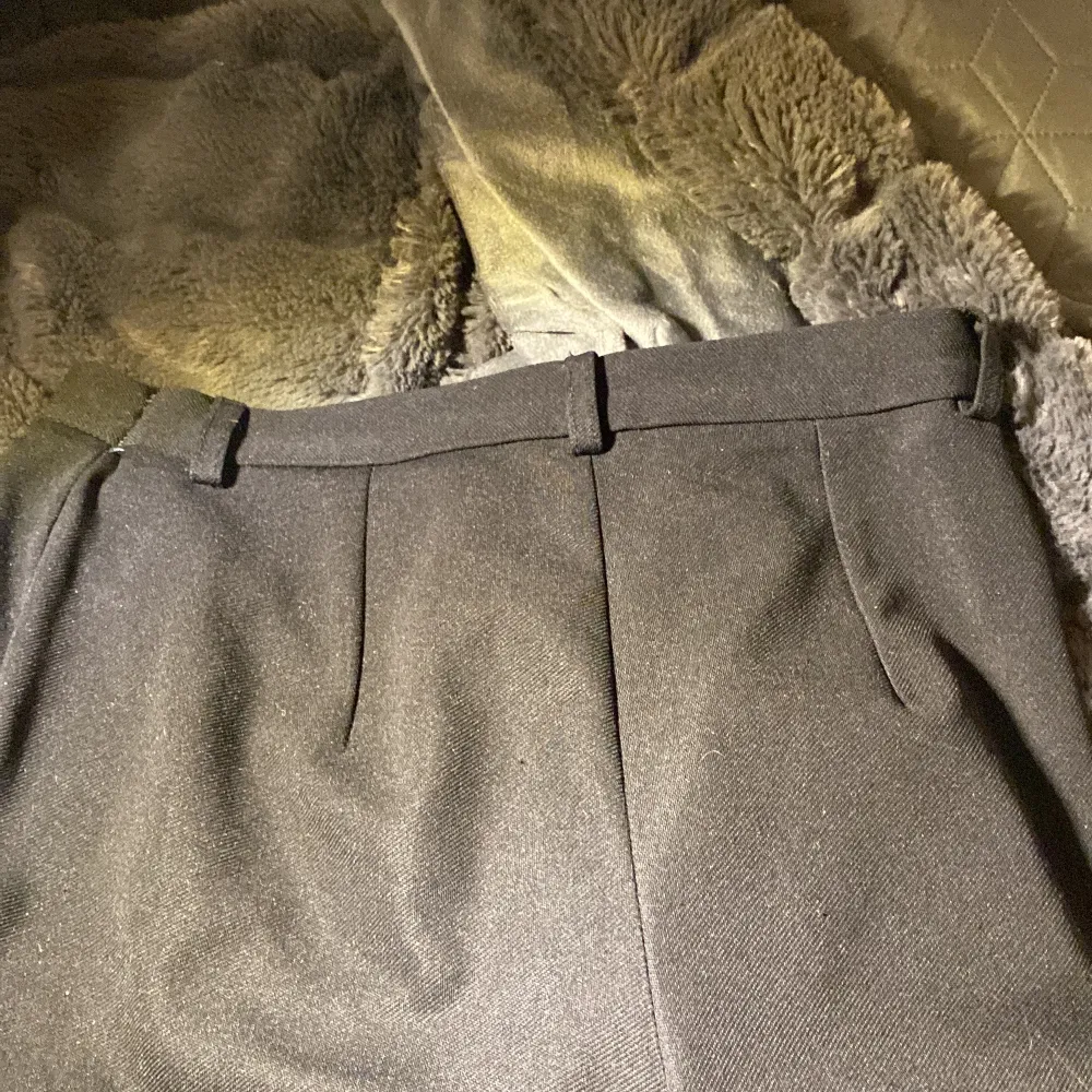 Snygga svarta kostymbyxor i klassisk stil. De har en knapp och dragkedja framtill samt hällor för bälte. Perfekta för en stilren look. Dem har lite små slit men har inga hål.. Farkut & Housut.
