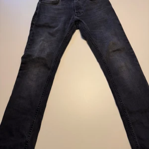 Svarta jeans från Nudie Jeans - Snygga svarta jeans från Nudie Jeans med klassisk femficksdesign och subtila detaljer. Perfekta för en stilren look. Märkeslogga på bakfickan och insidan av linningen ny pris 1600 mitt pris 600