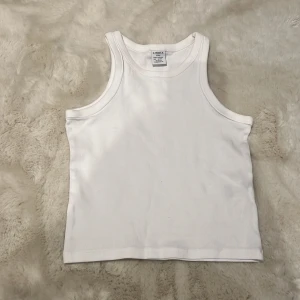 Vit ribbad linnetopp från Uniqlo - Säljer en stilren vit ribbad linnetopp från Lindex . Perfekt för varma dagar eller som lager under andra plagg. Enkel och klassisk design med rund halsringning.