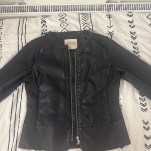 Svart skinnjacka från Censured - Snygg svart skinnjacka från Censured med dragkedja framtill. Jackan har en stilren design med långa ärmar och en figurnära passform. Perfekt för att ge din outfit en edgy touch.