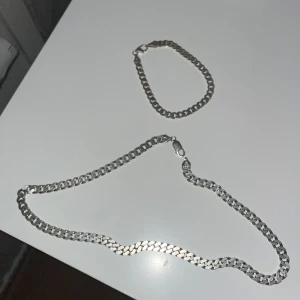 Silverfärgat halsband och armband - Säljer ett stilrent set med ett silverfärgat halsband och matchande armband. Båda har en pansar kedjedesign med karbinlås för säker stängning. Halsband har ring som som är ny men inte svetsats. Påverkar inte hållbarhet. Går inte av vid daglig användning kan hända om man badar eller idrottar med den annars är den som ny         Pris för båda 1100. Annars 500 armband 700-800kr halsband. Ask inkluderad