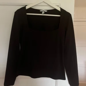 Svart långärmad topp - Säljer en stilren svart långärmad topp med fyrkantig halsringning. Perfekt för en minimalistisk look och kan enkelt matchas med olika outfits.