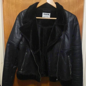 Svart skinnjacka  - Snygg svart skinnjacka från Bershka med dragkedjor och en mysig foder. Jackan har en klassisk bikerstil med en cool look. Perfekt för att ge din outfit en edgy touch. Pris kan diskuteras 