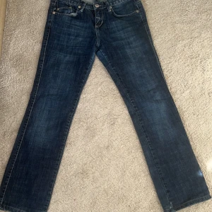 Victoria beckham jeans - Snygga blå jeans med unikt guldbroderi i form av kronor på bakfickorna. De har en klassisk femficksdesign och en rak passform. Perfekta för dig som vill sticka ut med stil!