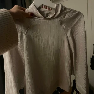 Vit blus med knappar🤍🤍🤍 - Elegant vit blus med långa ärmar och knappar i nacken. Materialet har en lätt glans och struktur som ger en lyxig känsla. Perfekt för en stilren look.