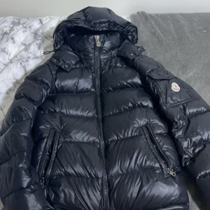 Svart dunjacka från Moncler - Snygg svart dunjacka från Moncler med huva och dragkedja. Jackan har en quiltad design och två praktiska fickor med dragkedja framtill. Perfekt för kyliga dagar jätte varm jacka och passar på vanliga dagar och kalla dagar . Moncler maya passar båda tjejer och killar storlek xs/S eller enligt moncler storlek 0. Kan mötas i Linköping och Norrköping priset kan diskuteras för mer bilder och information skriv till gärna 🫶🏽
