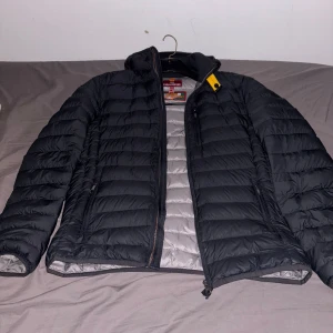 Svart dunjacka från Parajumpers - Säljer en svart dunjacka från Parajumpers. Jackan är superlätt och har en dragkedja framtill. Den är perfekt för kyligare dagar och har en stilren design med långa ärmar.