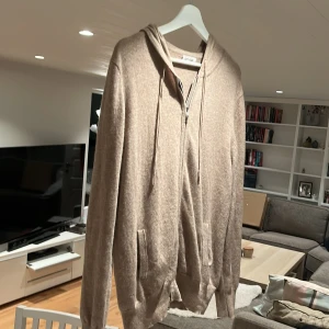 Beige hoodie från Soft Goat - Säljer en stilren beige hoodie från Soft Goat i storlek L. Tröjan har 2 stycken lagningar en som syns lite tydligare än den andra och en som är nästan helt osynlig. Därav lågt pris. Är redo att diskutera pris 