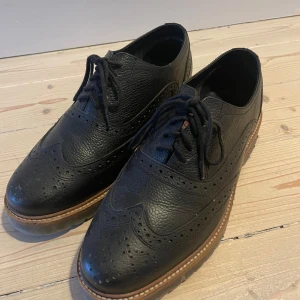 Svarta brogues från Ben Sherman - Snygga svarta brogues från Ben Sherman i skinn med klassisk snörning och dekorativa perforeringar. Skorna har en robust sula som ger bra grepp. Perfekta för en stilren look.