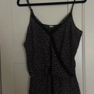 Blommig klänning från BikBok - Topp från BikBok i svart med små rosa och vita blommor. Säljs då den inte används men är i mycket bra skick. 