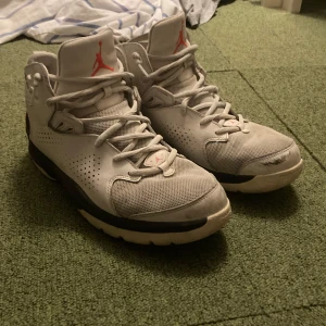Grå Nike Air Jordans - Säljer ett par grå Nike Air Jordans med klassisk design och röd logga. Skorna har snörning och perforerade detaljer för ventilation. Sulan är mönstrad för bra grepp.