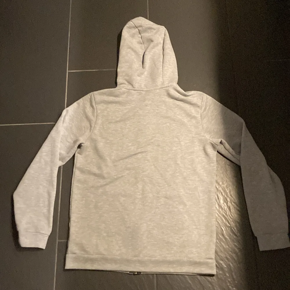 Säljer en grå hoodie från Nike i bra skick. Den har en dragkedja framtill och en justerbar huva med svarta snören. Perfekt för höst och vår, och den är superbekväm med långa ärmar och muddar. Passar både till träning och chill.. Tröjor & Koftor.